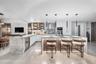 Gourmet kitchen featuring a waterfall-edge stone island, built-in wine refrigerator, under-cabinet lighting, floor-to-ceiling cabinetry, and modern pe