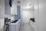 Laundry area featuring built-in cabinetry, an integrated stainless steel basin with a dual-handle faucet, stacked laundry appliances, and tile floorin