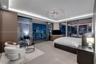 Floor-to-ceiling glass sliding doors, recessed cove lighting, sculptural multi-ring chandelier, large-format tile flooring, and integrated wood-veneer