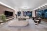 Floor-to-ceiling sliding glass doors, integrated cove lighting, wood-paneled accent wall with built-in media console, and large-format tile flooring