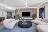 Living area featuring wood-paneled accent wall, floating media console, integrated vertical lighting, and sculptural chandelier