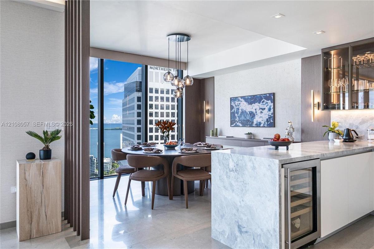 Kitchen featuring a stone waterfall island with integrated wine refrigeration, floor-to-ceiling windows, custom slat wood room divider, recessed light