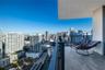 Private balcony featuring wood-finish tile flooring and a black metal railing overlooking the urban cityscape