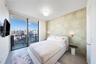 Floor-to-ceiling glass sliding doors, private balcony, polished concrete flooring, custom textured wall finish, and wall-mounted brass lighting fixtur