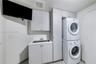 Laundry room featuring cabinetry with light-colored laminate finishes, a rectangular drop-in sink, and a vertical stacked laundry center