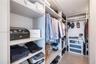 Walk-in closet featuring extensive built-in shelving, integrated hanging rods, and built-in drawer units with glass-front detailing