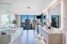 Floor-to-ceiling windows, dual-sink vanity with wood-finish cabinetry, stone countertop, glass-enclosed shower, and built-in soaking tub