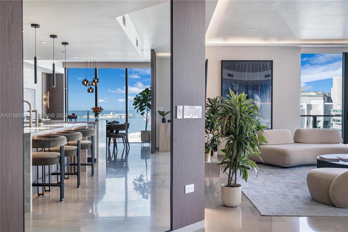 Open-concept floor plan featuring floor-to-ceiling windows, polished stone flooring, custom kitchen cabinetry with stone countertops, and recessed per