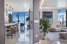 Open-concept floor plan featuring floor-to-ceiling windows, polished stone flooring, custom kitchen cabinetry with stone countertops, and recessed per