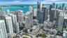 Aerial perspective featuring a high-density urban skyline, prominent waterfront, multi-level structures with green roof elements, and integrated eleva