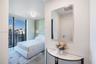 Floor-to-ceiling windows, private balcony, wall-mounted light fixture, textured accent wall, and stone-finish flooring