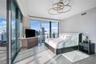 Floor-to-ceiling glass walls, expansive balcony access, polished stone flooring, custom orbital ceiling lighting, and textured wall finish