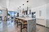 Kitchen featuring a stone-topped waterfall island, built-in stainless steel appliances, floor-to-ceiling cabinetry, stone flooring, and contemporary p