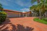 Single-story residence featuring a tile roof, decorative stone chimney exterior, spacious stamped concrete driveway, and established palm trees