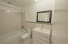Bathroom featuring a white vanity cabinet with a rectangular integrated sink, neutral stone-finish tile wainscoting with a glass mosaic accent border,