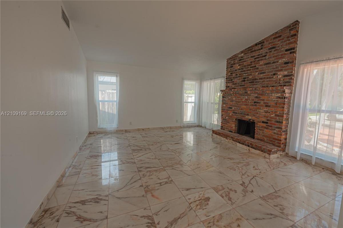 Vaulted ceiling, floor-to-ceiling brick fireplace with a raised hearth, and polished stone-finish tile flooring