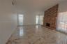 Vaulted ceiling, floor-to-ceiling brick fireplace with a raised hearth, and polished stone-finish tile flooring