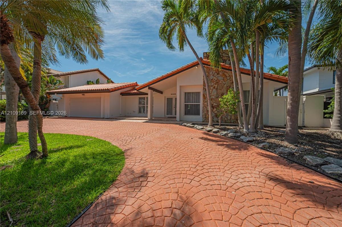 Single-story exterior featuring a stamped concrete driveway, decorative stone facade, tile roof, and attached garage