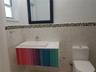 Wall-mounted floating vanity with a rectangular vessel sink and multi-colored paneling, complemented by a mosaic tile backsplash, framed wall mirror, 
