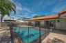 Exterior space featuring an in-ground swimming pool, terracotta-colored roof tiles, light-toned masonry walls, and brick-paver hardscaping