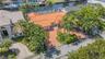 Waterfront property featuring a clay tile roof, paved driveway, and mature landscaping