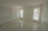 Interior space featuring neutral tile flooring, two sets of white louvered-door closets, and dual windows