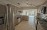 Kitchen featuring wood-finish cabinetry, stone-surface countertops, stainless steel appliances, ceramic tile flooring, and adjustable track lighting