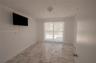 Large-format tile flooring, flush-mount ceiling lighting, and a window with a curtain rod