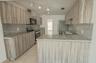 Kitchen featuring wood-grain cabinetry, stone countertops, tiled flooring, track lighting, and stainless steel appliances