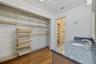 Vanity with stone countertop, undermount sink, and metallic faucet, complemented by wood-finish flooring and built-in closet shelving with integrated 