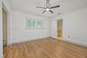 Bedroom 3 - Room featuring wood-finish flooring, crown molding, plantation shutters, and a central ceiling fan with integrated lighting