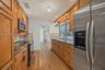Kitchen featuring wood cabinetry, stone-finish countertops, stainless steel appliances, wood-finish flooring, and recessed lighting