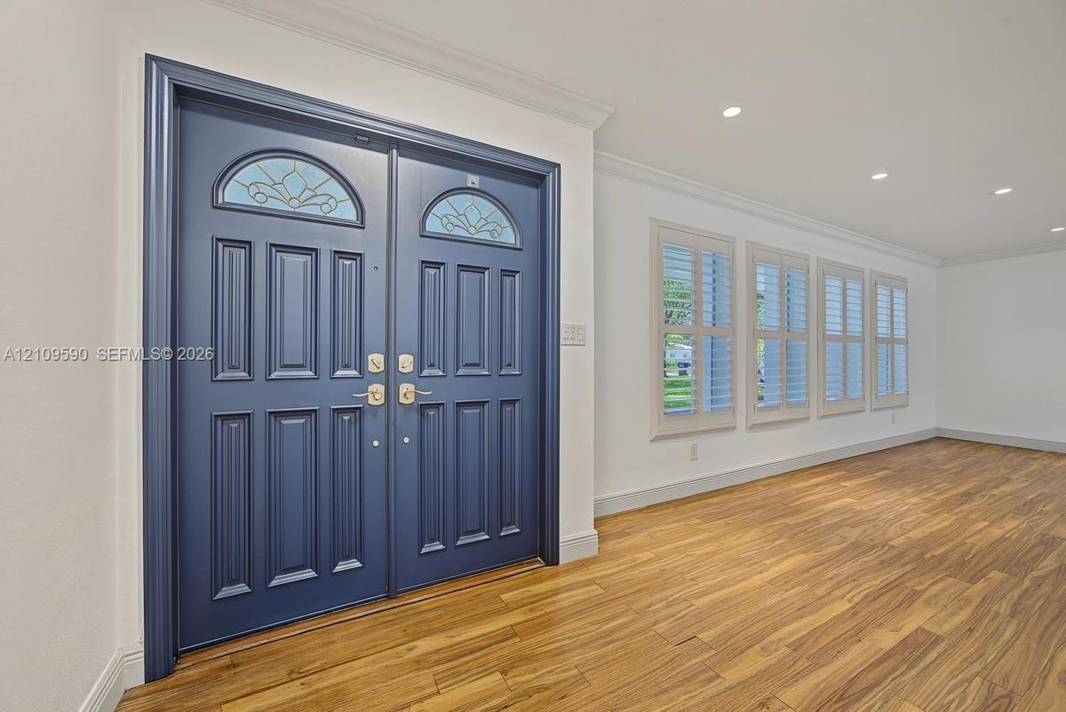 Double entry doors featuring leaded glass fanlights, recessed ceiling lighting, wood-finish flooring, and white plantation shutters