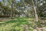 Expansive backyard featuring mature hardwood trees, natural terrain, and perimeter wood fencing