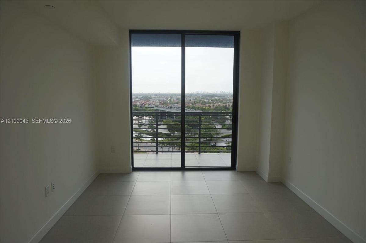 Large-format tile flooring, black-framed sliding glass doors, and a private balcony featuring metal railings and exterior tile flooring
