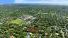 Aerial perspective of a sprawling property featuring dense mature tree canopy and expansive grounds situated within a verdant residential setting