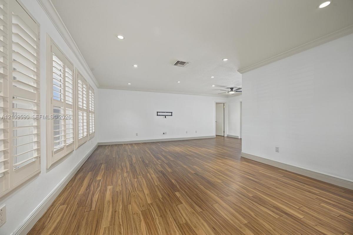 Living area featuring wood-finish flooring, recessed lighting, crown molding, and plantation shutters