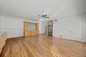Open floor plan featuring wood-finish flooring, built-in wooden cabinetry with tiled backsplash, recessed ceiling lighting, a central ceiling fan, and