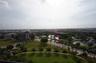 Elevated perspective featuring landscaped green space, mature palm trees, a central pond, and a horizon cityscape
