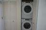 Stacked laundry center featuring a white Whirlpool front-load washer and dryer enclosed by white louvered bifold doors