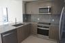 Kitchen featuring flat-panel wood-finish cabinetry, speckled stone countertops, a full-height stone backsplash, and stainless steel appliances includi