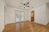 Room featuring wood-finish flooring, crown molding, ceiling-mounted light fixture with fan, and double glass doors with built-in shutters