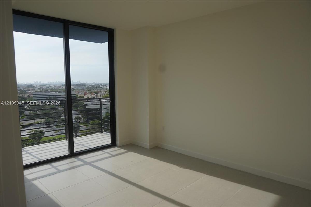 Floor-to-ceiling sliding glass doors, private balcony with metal railing, and neutral tile flooring
