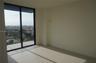Floor-to-ceiling sliding glass doors, private balcony with metal railing, and neutral tile flooring