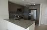 Kitchen featuring stone countertops, flat-panel cabinetry, stainless steel appliances, a breakfast bar, and track lighting