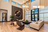 Double-height ceilings featuring floor-to-ceiling windows, wood-finish flooring, vertical slat accent wall, and a multi-tiered modern chandelier