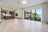 Open-concept living space featuring large-format tile flooring, a kitchen with dark-finish cabinetry, built-in stainless steel appliances, tiered pend