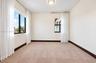Neutral wall-to-wall carpeting, dual black-framed windows, and a flush-mount overhead light fixture