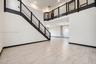 Double-height ceiling, open-concept floor plan, staircase with metal horizontal railing, balcony landing, and neutral tile flooring