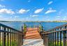 Private dock featuring composite decking, vertical wood pilings, and black metal railings with nautical rope accents